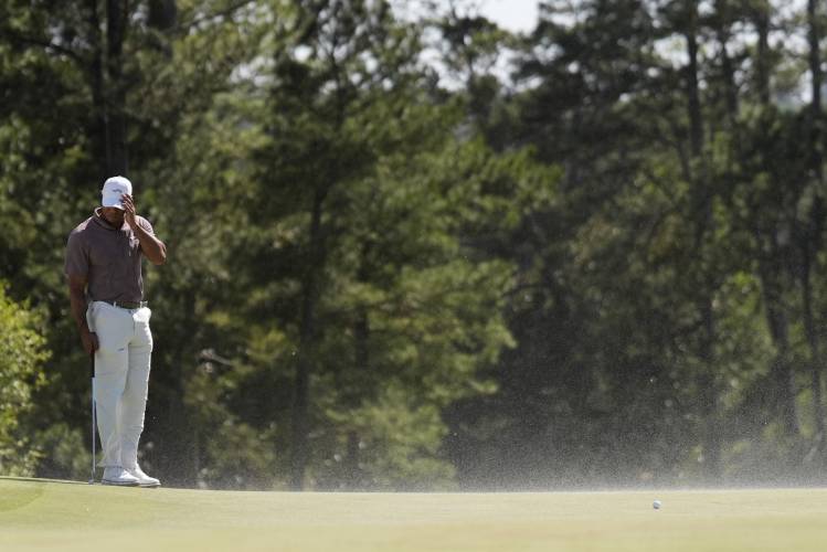 Tiger Woods shields his face from the blowing sand on the 18th hole during second round at the Masters golf tournament at Augusta National Golf Club Friday, April 12, 2024, in Augusta, Ga. (AP Photo/Ashley Landis)