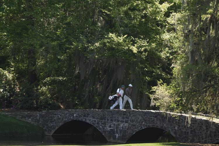 Tiger Woods walks over the Byron Nelson Bridge on the 13th hole during second round at the Masters golf tournament at Augusta National Golf Club Friday, April 12, 2024, in Augusta, Ga. (AP Photo/Charlie Riedel)