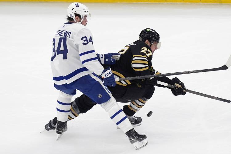 Toronto Maple Leafs' Auston Matthews (34) and Boston Bruins' Hampus Lindholm (27) vie for the puck during the first period in Game 1 of an NHL hockey Stanley Cup first-round playoff series Saturday, April 20, 2024, in Boston. (AP Photo/Michael Dwyer)