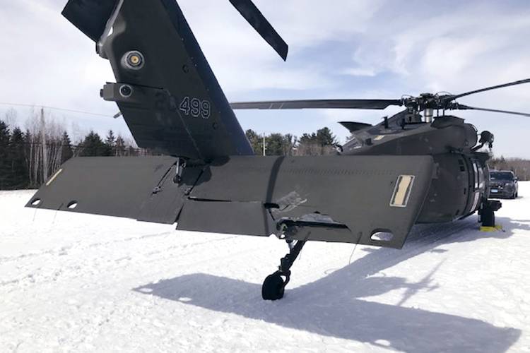 A damaged Black Hawk helicopter rests on the snow, March 13, 2019, in Worthington. A Massachusetts man wants the government to pay nearly $10 million after being badly injured in a crash with a Black Hawk helicopter. The lawsuit filed by Jeffrey Smith against the government follows a 2019 crash in which Smith’s snowmobile collided with the helicopter that was parked on a trail at dusk. 