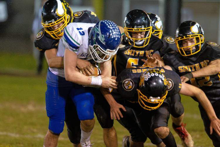 Smith Vocational’s John Loiko (35), left, wraps up Blue Hills running back Aidan Landers (12) with a host of Viking defenders in the third quarter Friday night in Northampton.