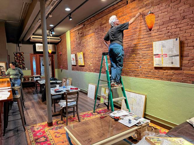Artist Amanda Barrow hangs work for her show, “The Asian Wall Series,” at Rhynia in Northampton, a new arts and community space.