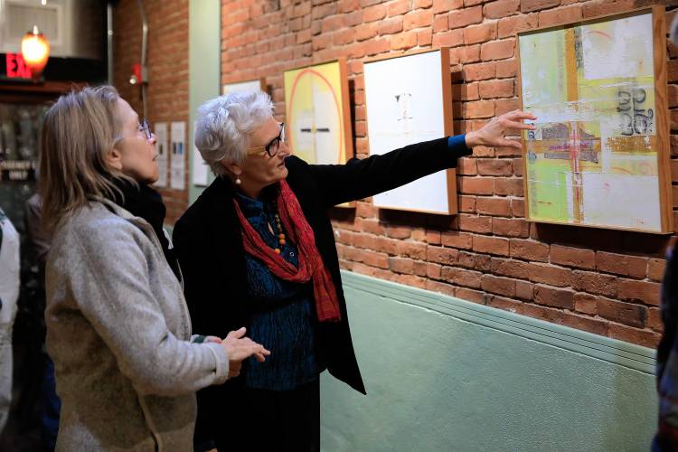 Easthampton artist Amanda Barrow, right, discusses a painting in her exhibit, “The Asian Wall Series,” with Janine Norton at Rhynia, a new arts and community space in Northampton.