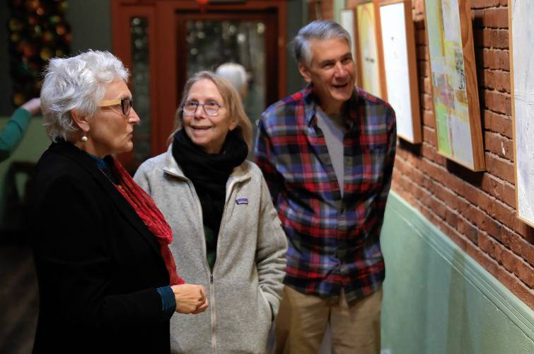 Easthampton artist Amanda Barrow, left, discusses her exhibit, “The Asian Wall Series,” with Janine Norton and Robert Jabaily at Rhynia, a new arts and community space in Northampton.