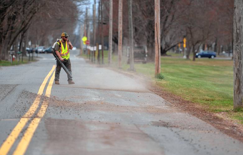 Thaddeus Mish, an employee of the Hadley Department of Public Works, cleans up gravel and dirt on West Street  one afternoon last week. 