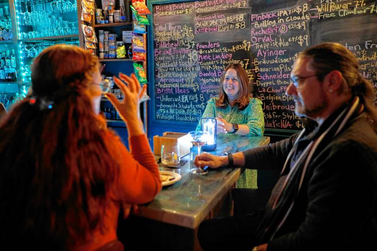 Owner Juliette Mooers, middle, talks with bar patrons Beth McElhiney, left, and Jeff Sinkwich on Friday night at Valley Art Supplies in Easthampton.
