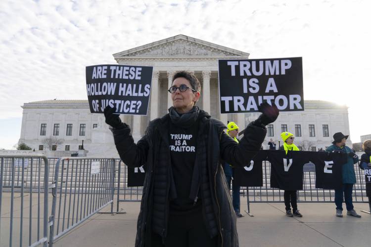 Demonstrators hold up signs outside of the U.S. Supreme Court, Thursday, Feb. 8, 2024, in Washington. The U.S. Supreme Court on Thursday will take up a historic case that could decide whether Donald Trump is ineligible for the 2024 ballot under Section 3 of the 14th Amendment. (AP Photo/Jose Luis Magana)