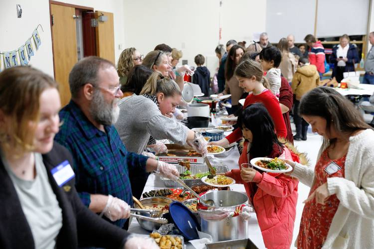 Faculty members serve a potluck meal for hundreds of students and their families Thursday during the annual International Night at Sunderland Elementary School. 