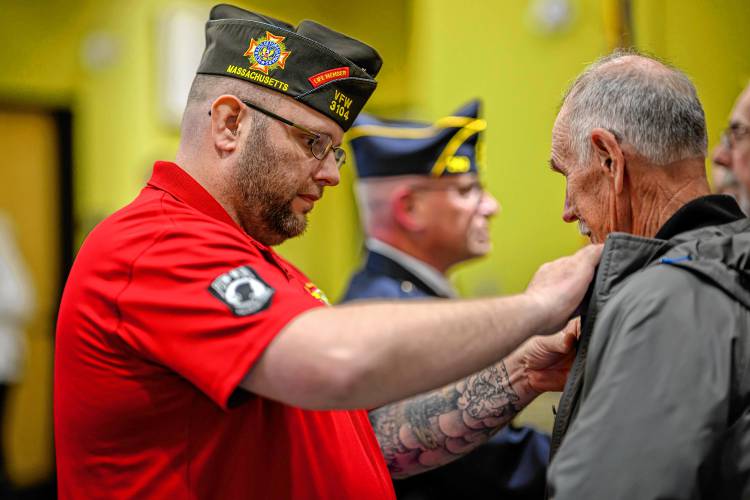 South Hadley veterans’ agent Michael Slater pins new members during South Hadley’s National Vietnam War Veterans Day Commemoration at the South Hadley Public Library on Thursday.