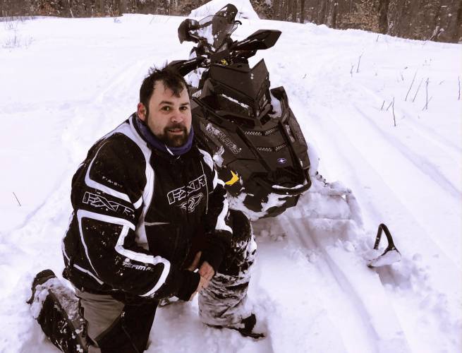  Jeffrey Smith poses with a snowmobile during March 2018, in Windsor, Mass. Jeffrey Smith has filed suit against the government to pay nearly $10 million after being badly injured in a snowmobile crash in 2019 with a Black Hawk helicopter. Smith’s snowmobile collided with a helicopter that was parked on a Massachusetts snow-covered trail at dusk.