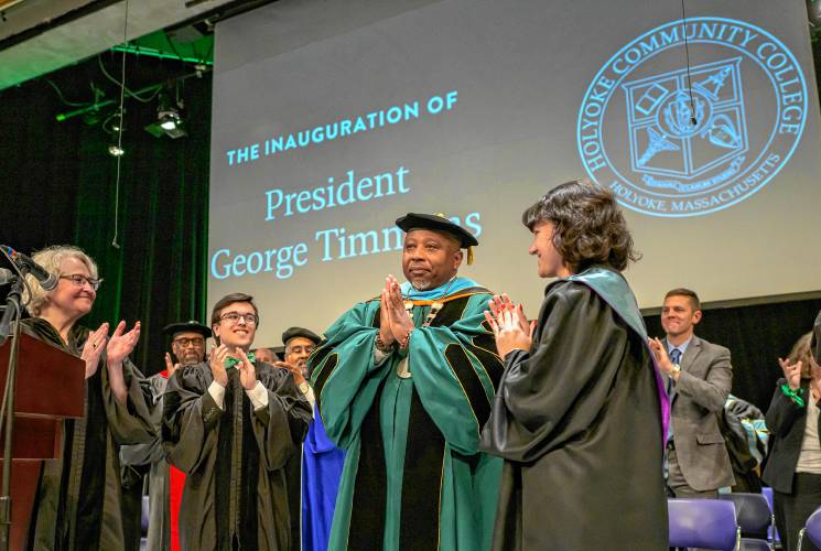 George Timmons, acknowledges applause as Vanessa Smith, Holyoke Community College interim chair of the board of trustees, left, along with students Barney Garcia, second from left, and Alicia Beaton, right, look on as Timmons is installed as the fifth president of Holyoke Community College during an inauguration ceremony in Holyoke on Friday, April 19, 2024.
