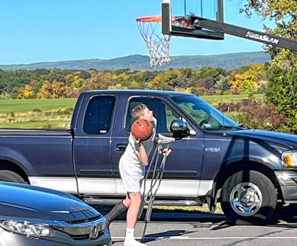 Owen Earle shoots hoops while on crutches outside of his house in Hadley, Mass.