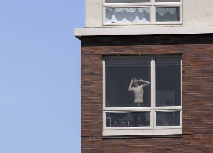 A resident of a downtown apartment complex glances out of his window as the eclipse begins over Columbia, Mo., on Monday, April 8, 2024. (Brian W. Kratzer/Missourian via AP)