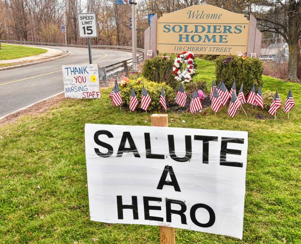 Signs, flags, flowers and wreaths are placed at the entrance to the Soldiers’ Home in Holyoke, Wednesday, Apr. 8, 2020.