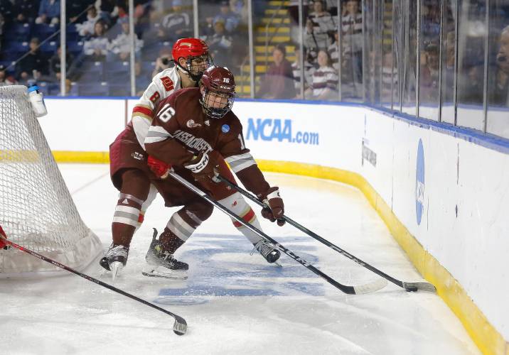 UMass forward Aydar Suniev (16) maneuvers the puck under pressure from Denver defenseman Shai Buium (8) in the first period of overtime during the opening round of the NCAA tournament Friday at the MassMutual Center in Springfield.