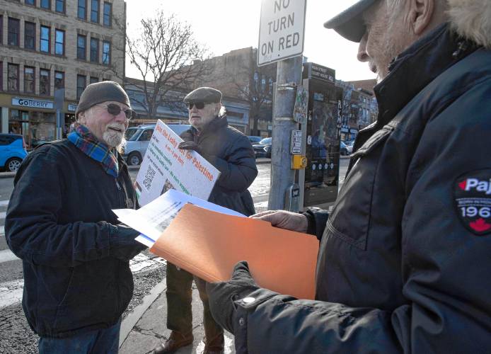 Fergus Marshall listens as Peter Kakos and Nick Mottern hand out flyers on their call to fast for a cease-fire in Palestine on Thursday on Main Street in Northampton. “It’s an act of desperation,” said Kakos.