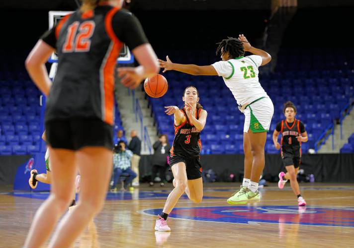 South Hadley’s Maddie Soderbaum (3) sends a pass up court to Cara Dean (12) past Cathedral’s E' Mani Richardson (23) in the fourth quarter of the MIAA Div. 4 girls basketball state final Sunday afternoon at the Tsongas Center in Lowell.