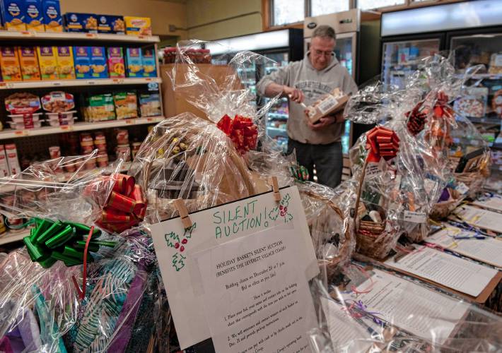 Roger Zimmerman, a volunteer a the Leverett Village Co-Op stocks shelves. In front of him are baskets which are part of a silent action fund raiser for the Co-Op.