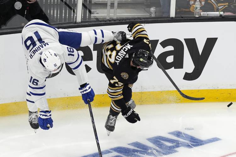Toronto Maple Leafs' Mitch Marner (16) and Boston Bruins' Charlie McAvoy (73) compete for the puck during the first period in Game 1 of an NHL hockey Stanley Cup first-round playoff series, Saturday, April 20, 2024, in Boston. (AP Photo/Michael Dwyer)