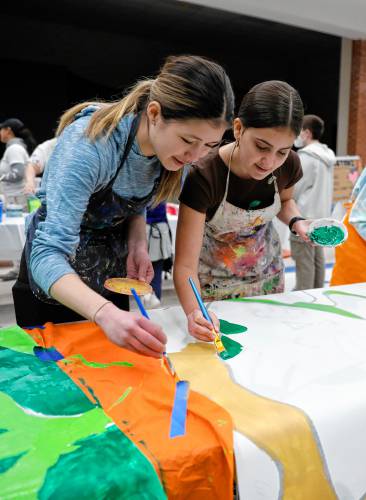 Adelaide Amias, 13, left, and Lucia Flajnik-Palladino, 13, paint one of 52 mural panels to help create a 1,500-square-foot mural for JFK Middle School during a community painting party Saturday afternoon in the school cafeteria.
