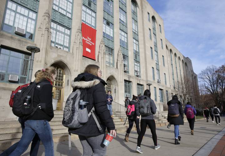 FILE - Students and passers-by walk past an entrance to Boston University College of Arts and Sciences, Nov. 29, 2018, in Boston. As more than 2 million graduating high school students from across the United States finalize their decisions on what college to attend this fall, many are facing jaw-dropping costs — in some cases, as much as $95,000. (AP Photo/Steven Senne, File)