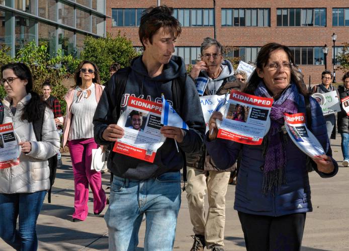 Iris Berkman walks with her son, Nadav Berkman, while holding a plate with a picture of one of her relatives, right, during an event sponsored by UMass Hillel called “Bring Them Home.” Participants carried plates with flyers that were attached. Each flyer had a picture of one of the 240 hostages kidnapped from Israel by Hamas. Each plate was than taped to tables in a symbolic ritual of Shabbat honoring the hostages.