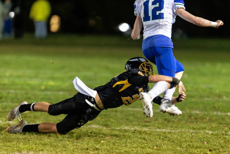 Smith Vocational’s Jameson Tobin (20) dives to stop a breakaway run from Blue Hills running back Aidan Landers in the second quarter Friday night in Northampton.