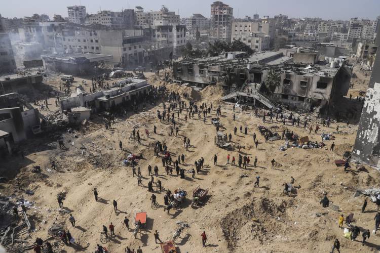 Palestinians walk through the destruction left by the IDF on the Gaza Strip near Shifa Hospital in Gaza City.