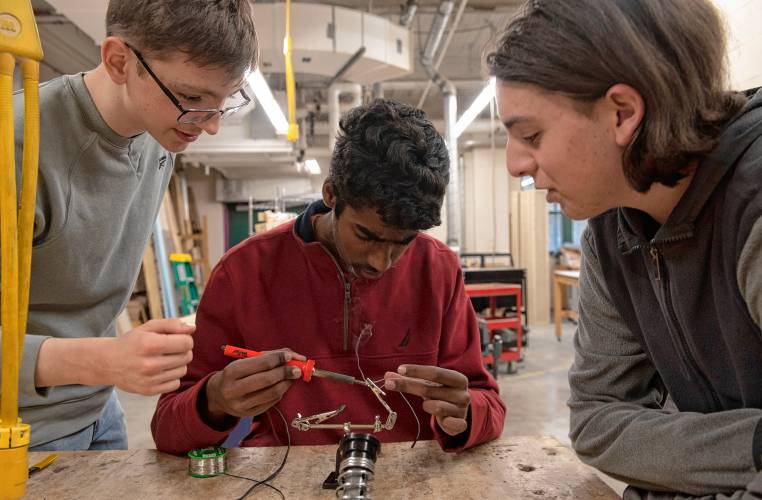 Will Larson, left, Yatharth Rajakumar and Max Costa, students at Amherst High School, work on soldering a chip that will be placed in the garment that is part of an InvenTeam project this year called SARAH, Search And Rescue Assistant Hardware. The project will transmit vital signs of search and rescue personnel while they are on a mission.