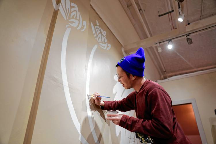 Small Victories owner Isa Wang works on a mural painting on the store walls Thursday afternoon ahead of the retail shop’s grand opening on Friday, March 29, inside Thornes Marketplace in Northampton. The shop will offer a variety of handmade wares from greeting cards that can be planted to grow herbs or wildflowers, and pins for easy identification of a person’s pronouns.