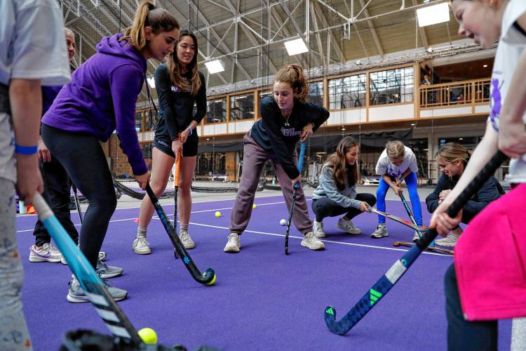 Members of the Amherst College women’s field hockey team practice techniques with a group of girls on National Girls and Women in Sports Day on Saturday. 