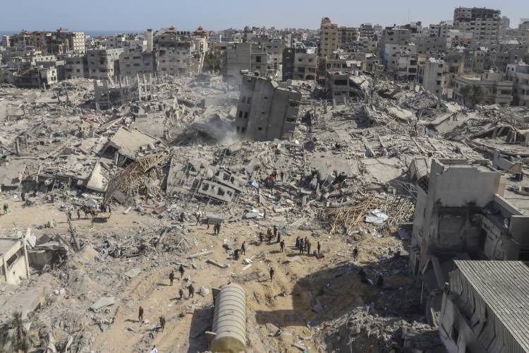 Palestinians walk through the destruction left by the Israeli air and ground offensive on the Gaza Strip near Shifa Hospital in Gaza City, Monday, April 1, 2024.