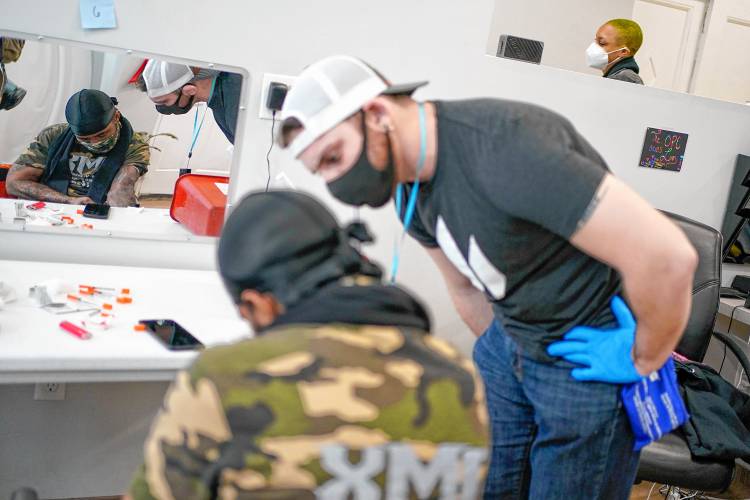 Brian Hackel, right, an overdose prevention specialist, helps Steven Baez, a client suffering addiction, at an overdose prevention center, OnPoint NYC, in New York in February 2022.
