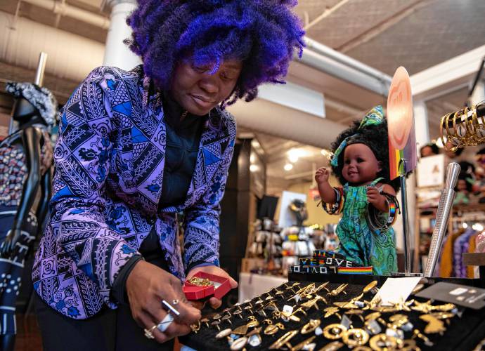 Aimee Salmon, owner of Positively Africana in Thornes Marketplace in Northampton, sets up her shop Tuesday  before opening. The store sells various wares, made by women from across Africa, including beadwork, clothing, handbags and traditional mud cloth, or fabric dyed with fermented mud.