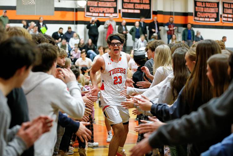 South Hadley’s Brady Currier runs through the tunnel of student fans after the Tiger’s 53-46 win against Granby on Wednesday night in South Hadley.