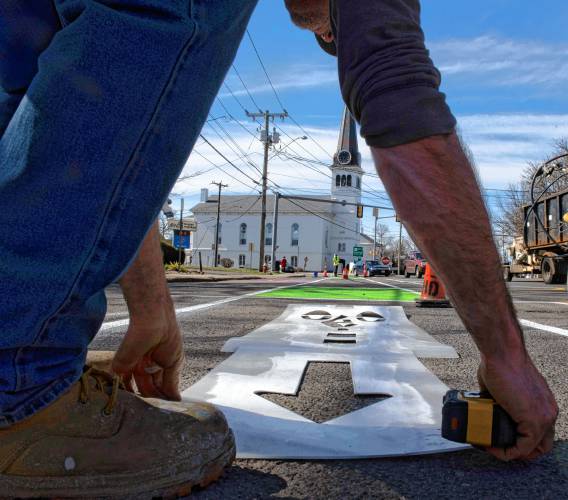 Phil LaFlamme, an employee of the Easthampton Highway Department, paints a bike lane symbol on a portion of  Easthampton’s Main Street experimental redesign. 