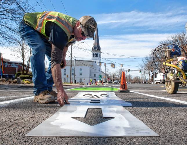 Phil LaFlamme, an employee of  the Easthampton Highway Department, paints a bike lane symbol on a portion of the Easthampton Main street  experimental redesign. 