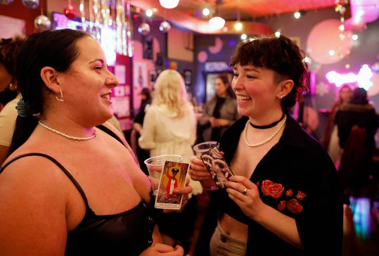 Mallory Bauer, left, and Hope Wampler converse after being matched with their tarot cards that were given out during the Sapphic Social event at the Majestic Saloon in Northampton.
