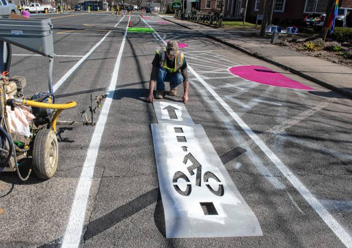 Phil LaFlamme, an employee of  the Easthampton Highway Department, paints a bike lane symbol on a portion of the Easthampton Main street  experimental redesign. 