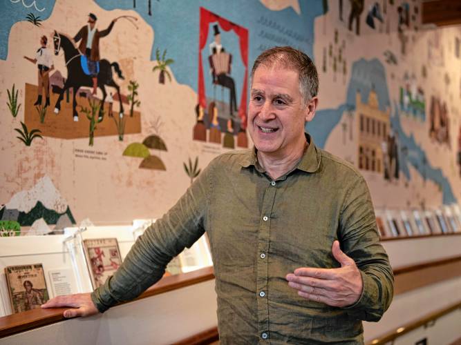 David Mazower, lead curator for “Yiddish: A Global Culture,” talks about the new exhibit. Behind him is a mural that highlights Yiddish cultural figures and institutions from around the world, including Jewish gauchos in Argentina.