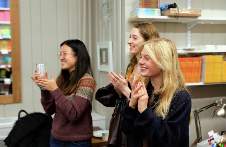 Priscilla Lee, from left, Pauline Bissell and Héloïse Schep applaud while Ilan Stavans speaks during the recent opening celebration of Restless Books in Amherst.