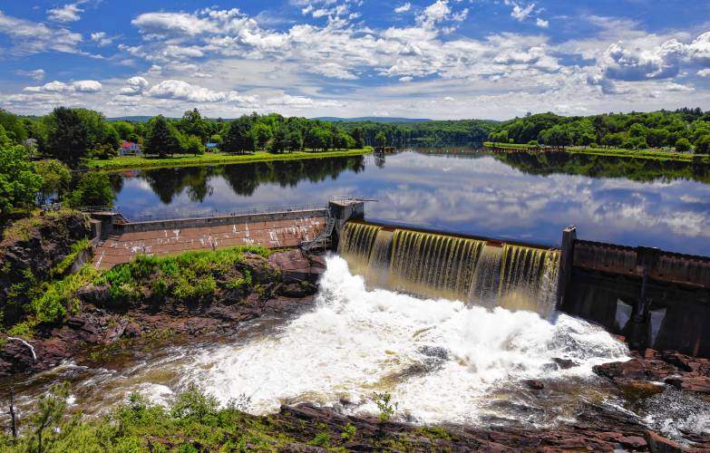 The calm flowing waters of the Connecticut River reflect the sky before plummeting onto the rocks below the Turners Falls Dam.