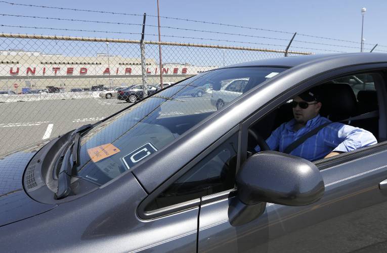  In this July 15, 2015 file photo, Uber driver Karim Amrani sits in his car parked near the San Francisco International Airport parking area in San Francisco. 