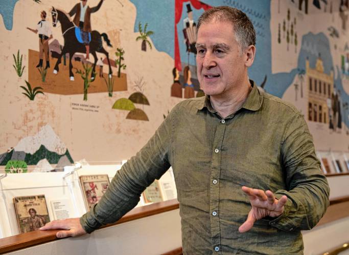 David Mazower, lead curator for “Yiddish: A Global Culture,” talks about the new exhibit at the Yiddish Book Center. Behind him is a new mural that highlights Yiddish cultural figures and institutions from around the world, including “Jewish gauchos” in Argentina.