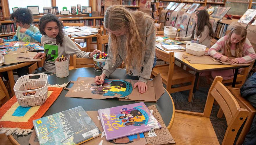 Molly Valentine, a Crocker Farm Elementary student, works with other students on panels for the Memory Project spearheaded by librarian and teacher Waleska Santiago-Centeno. For the project students created hanging banners featuring women from picture books they have read in the library.
