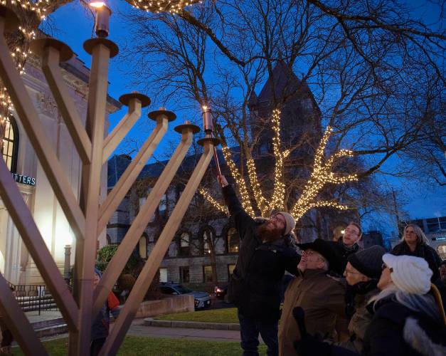 Rabbi Tuvia Helfen lights the candle for the first day of Hanukkah during an event on Main Street in Northampton last Thursday night where community gathered to sing and celebrate. 