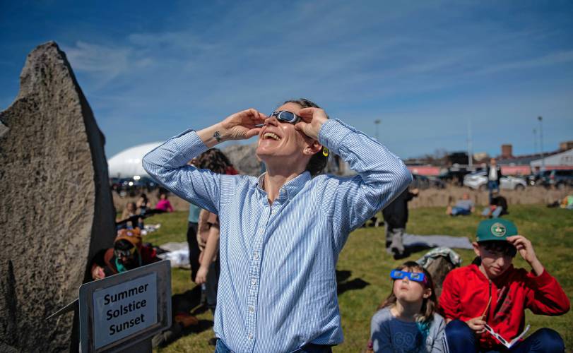 Katharine Waggoner gets her first look at the eclipse at the UMass Sunwheel on Monday afternoon while there with her two children, Elizabeth Stoffer and John Melaney. 