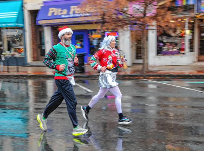 Fun run participants Carl Binner, left, and Deborah Day, both of Sunderland, stride along Northampton’s Main Street on Sunday during the 20th annual Hot Chocolate Run to raise money for Safe Passage’s mission to provide support and services to survivors of domestic violence.