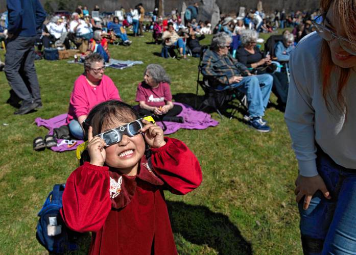 Josie Liang uses the glasses to look a the eclipse at the UMass Sunwheel  on Monday afternoon. Liang was there with her mother, Xu Chen. 