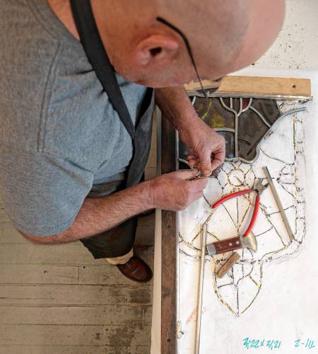 Glenn Shalan works on a window in his Easthampton studio.
